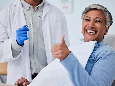 Patient smiling as dental assistant takes notes on clipboard