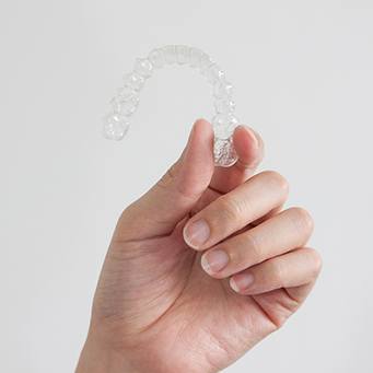 Smiling patient holding clear aligners