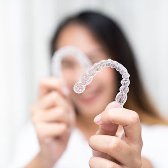 Dentist putting clear aligner on model of teeth