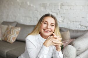 Smiling older woman with nice teeth sitting in her living room