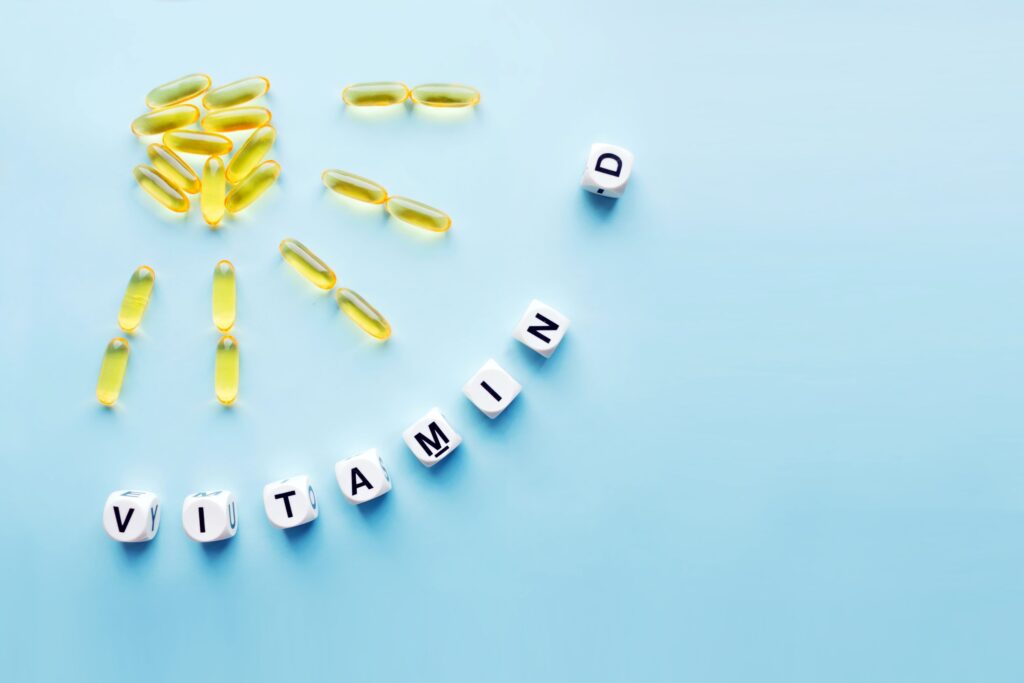 Yellow supplements arranged like sunshine next to dice spelling "VITAMIN D"