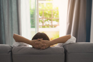 Woman resting on couch with hands behind head